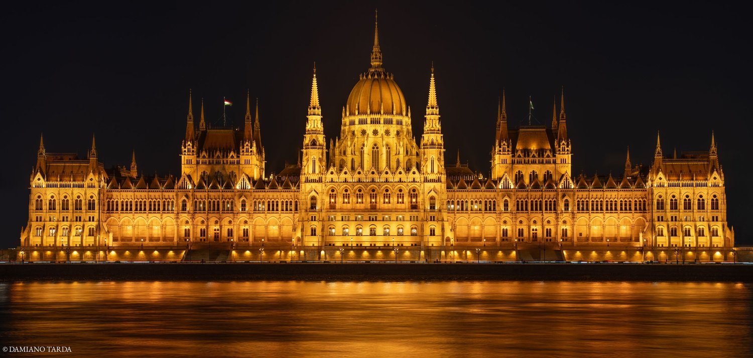 budapest notturna, parlamento illuminato con riflessi sul Danubio.